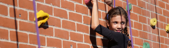 young girl climbing on a climbing wall